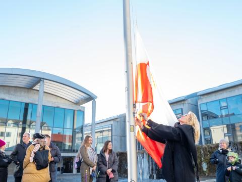 Heiða Björg Hilmisdóttir borgarstjóri dregur grænlenska fánann að húni við Ráðhús Reykjavíkur. Ráðhús og áhorfendur í bakgrunni.