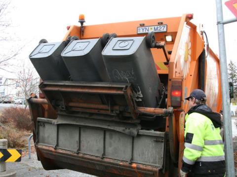 Starfsmaður sturtar úrgangi úr tunnum í sorphirðubíl.