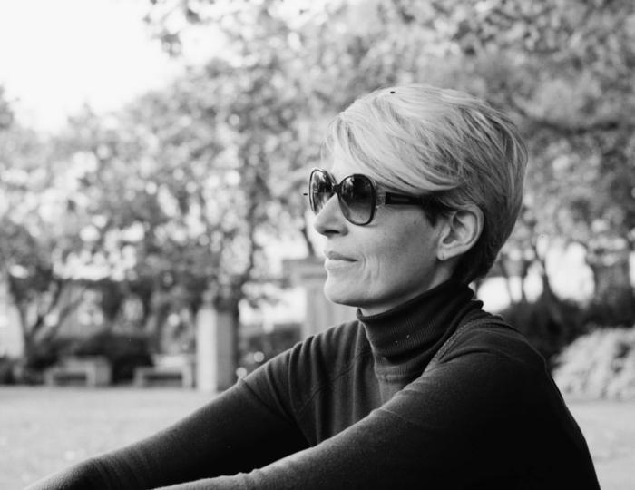 Woman with sunglasses sitting outdoors in nature.
