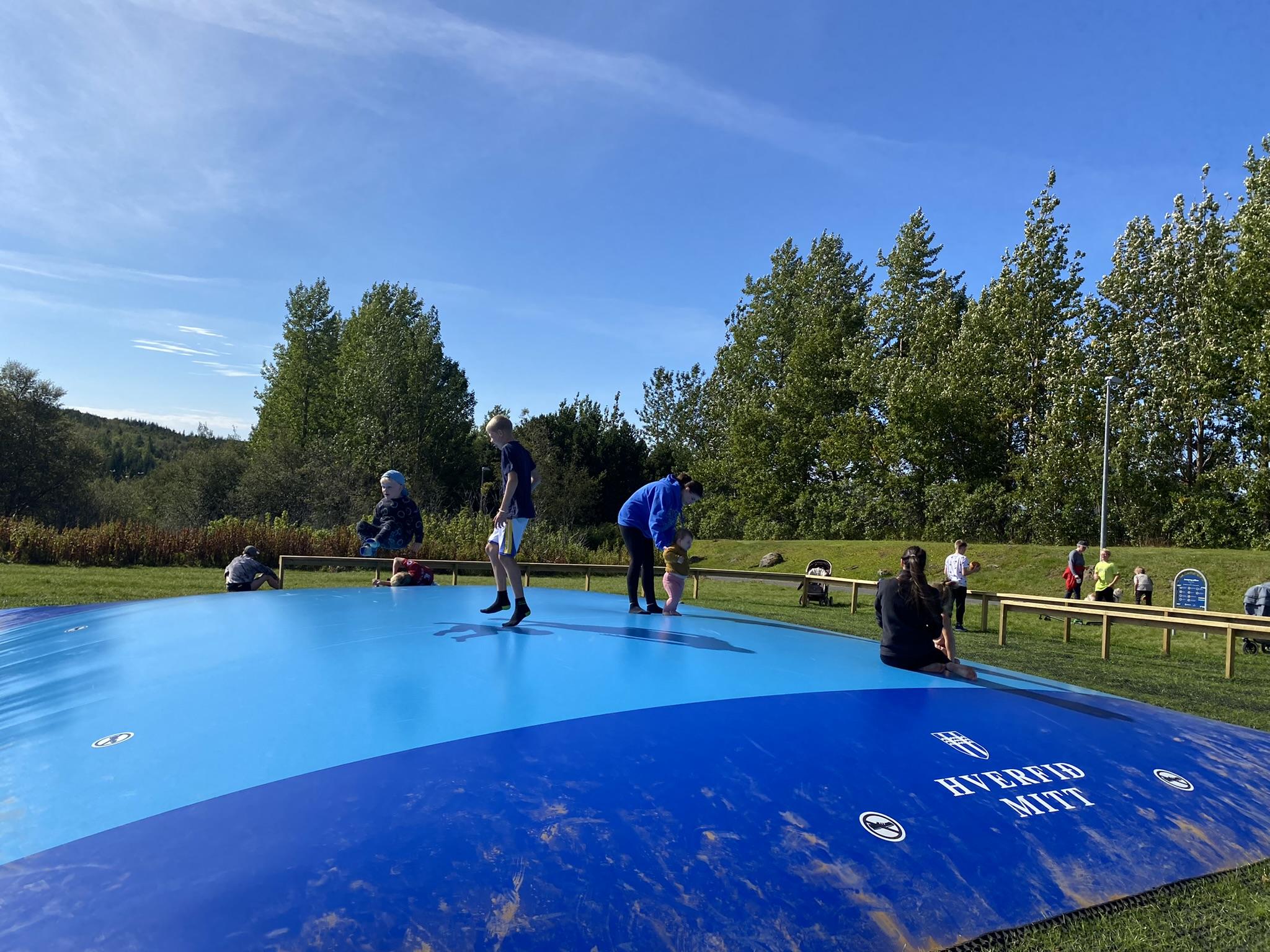 Hoppandi börn og fullorðnir á ærslabelg í Árbæ.