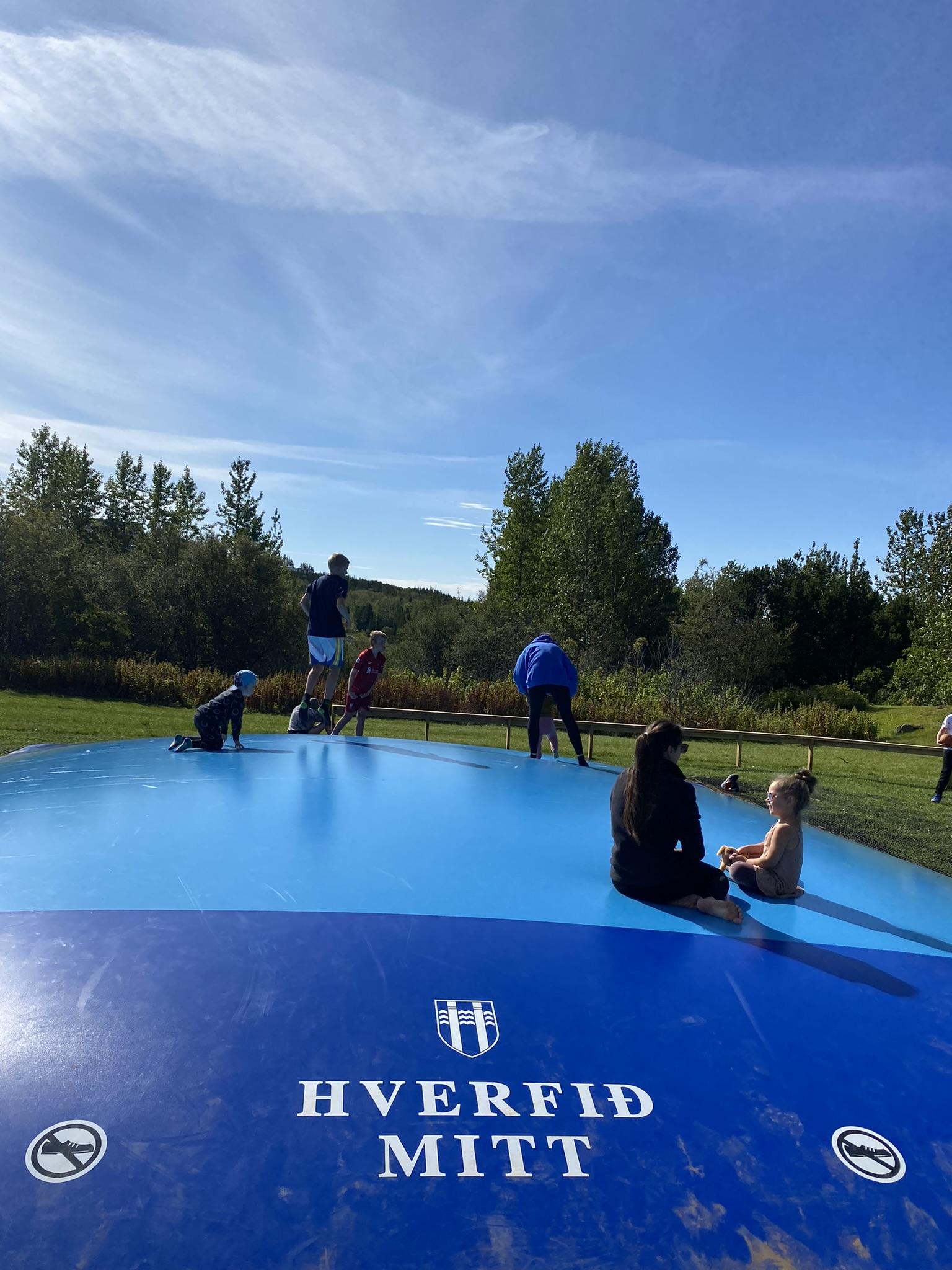 Fólk á sumardegi á ærslabelg í Árbæ.