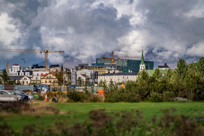 Byggingarkranar, grænt svæði og hús í Reykjavík.
