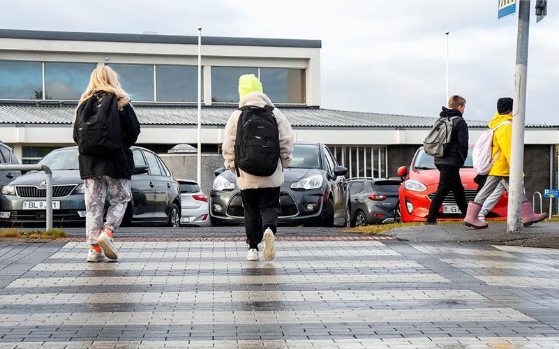 Grunnskólakrakkar ganga yfir gangbraut á leið í skólann.
