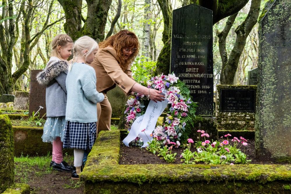 Þórdís Lóa Þórhallsdóttir, forseti borgarstjórnar, leggur blómsveiginn á leiði Bríetar Bjarnhéðinsdóttur, hjá henni standa Diljá Daðadóttir og Vaka Fannarsdóttir sem báru kransinn.