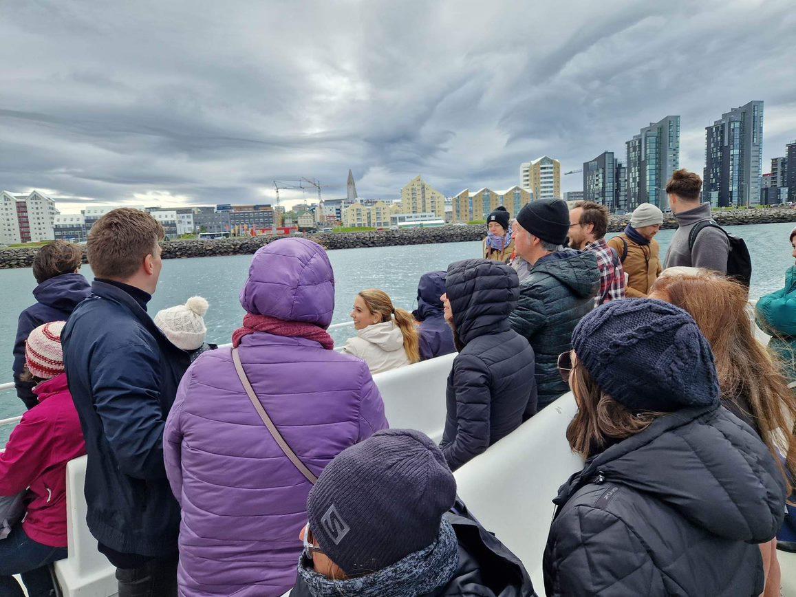 Horft aftan á fólk í Viðeyjarferju, fólkið horfir til borgarinnar.