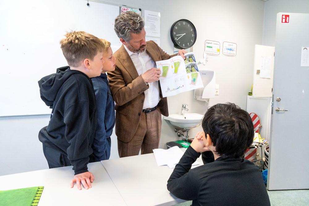 Dagur B. Eggertsson borgarstjóri veitir viðtöku undirskriftalista frá börnum í Landakotsskóla. Á myndinni sýnir hann strákunum sem stóðu að listanum, hvernig nýtt deiliskipulag á að líta út. Mynd úr skólastofu.