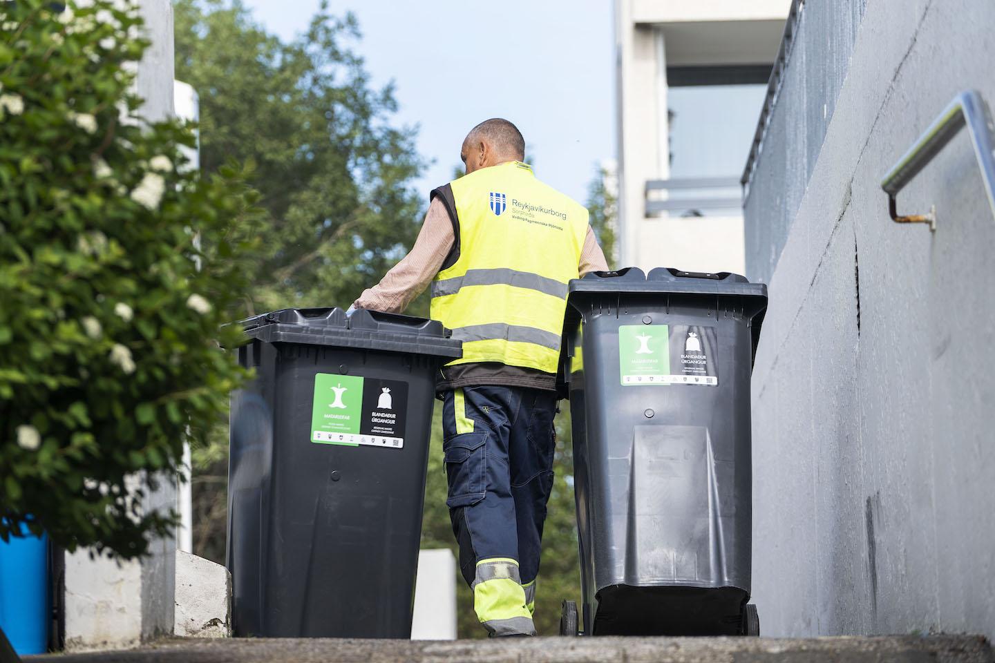 Waste collection worker with two waste bins.