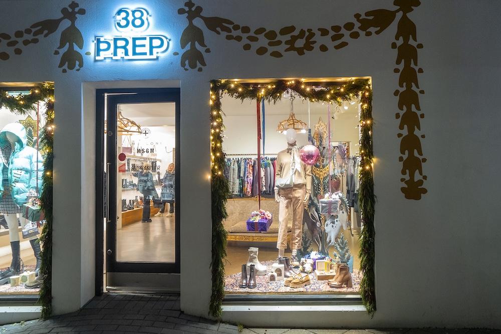 Upplýstur og jólaskreyttur búðargluggi.