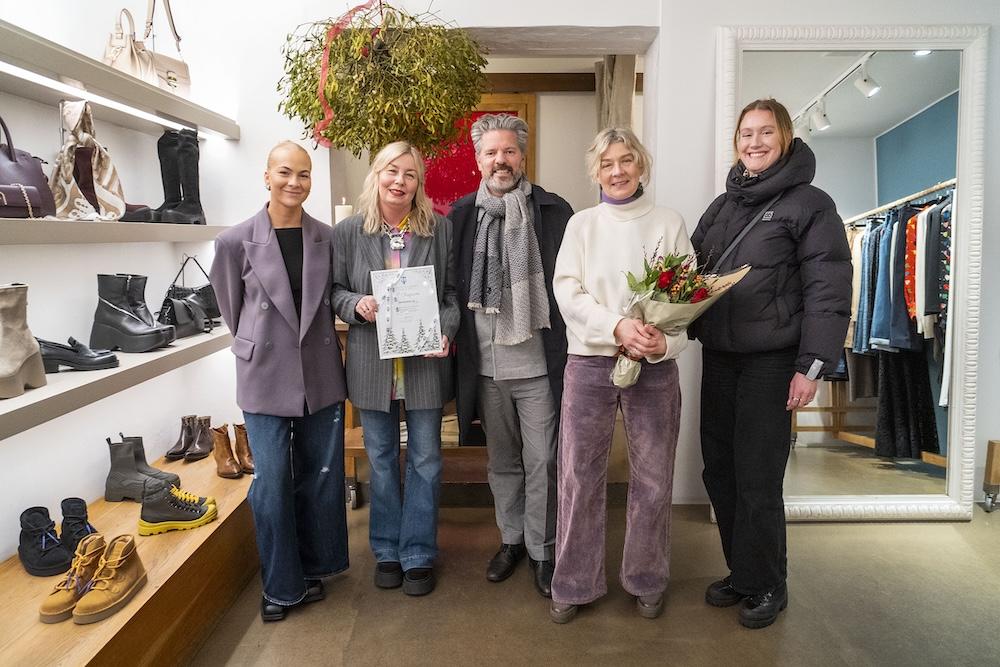 Fólk með blóm og verðlaun inni í verslun með föt og skó.