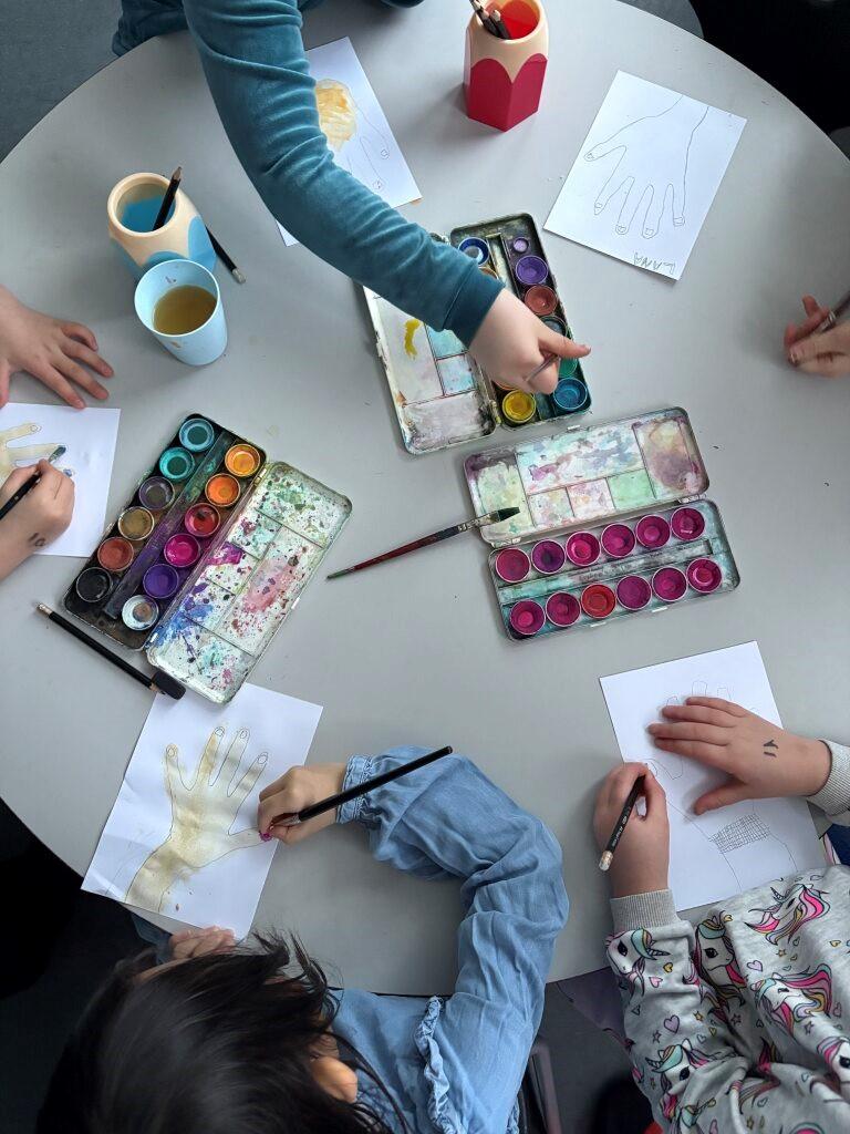 Börn að mála hendur á blað.