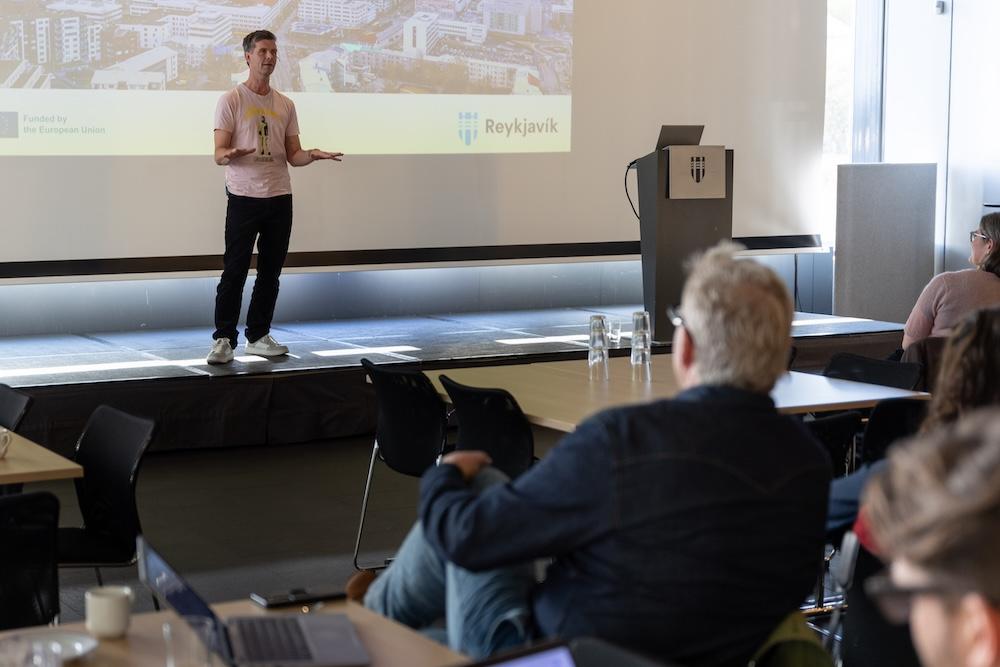 Man on stage speaking to people in the audience.