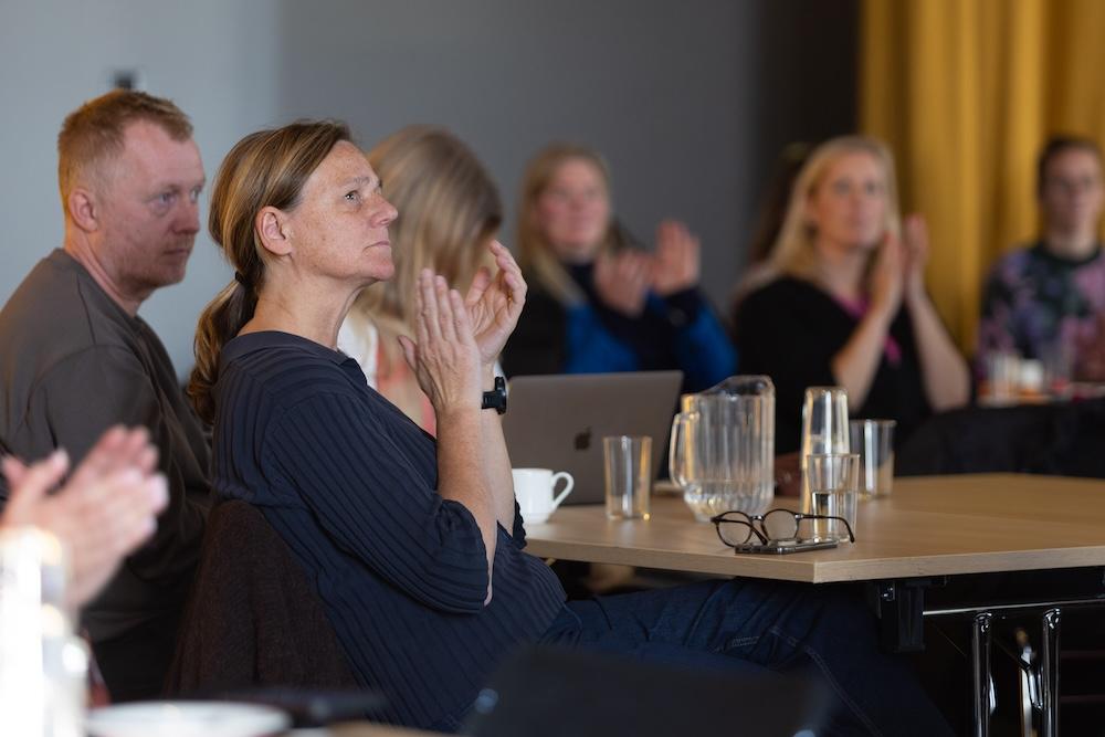 Woman clapping at table in the hall.