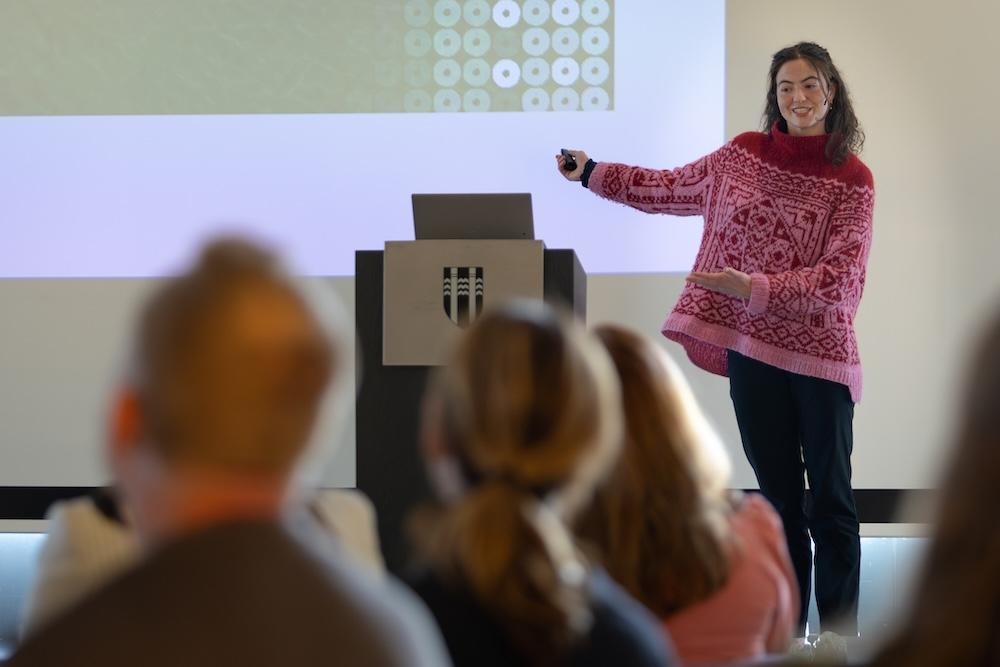 Woman on stage speaking to people in the audience.