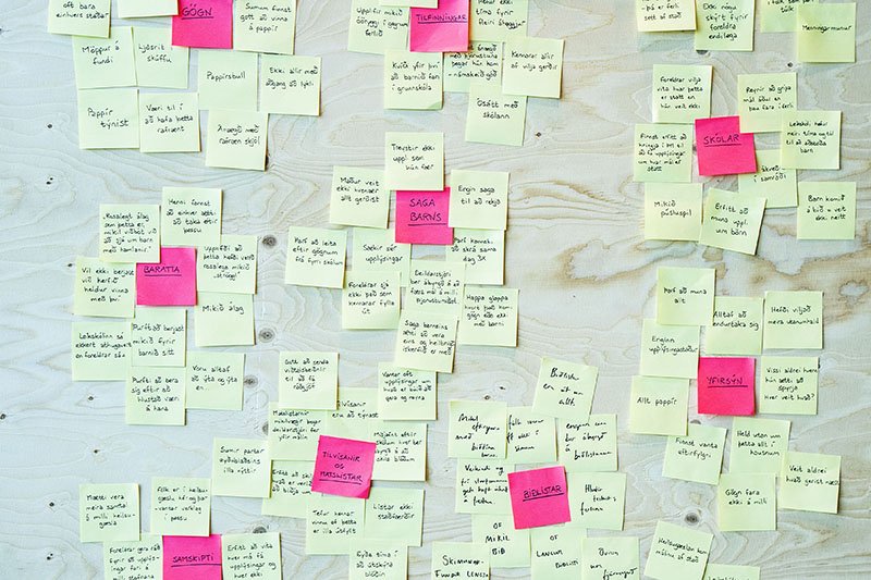 Mynd af post-it miðum á vegg í þemagreiningu.