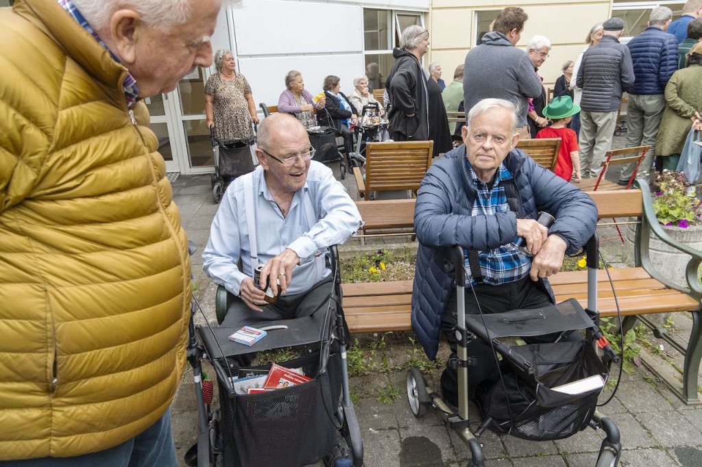Tveir menn sitja á bekk og ræða málin. 