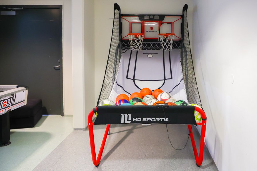 Small indoor basketball hoop with two baskets and multiple balls. 
