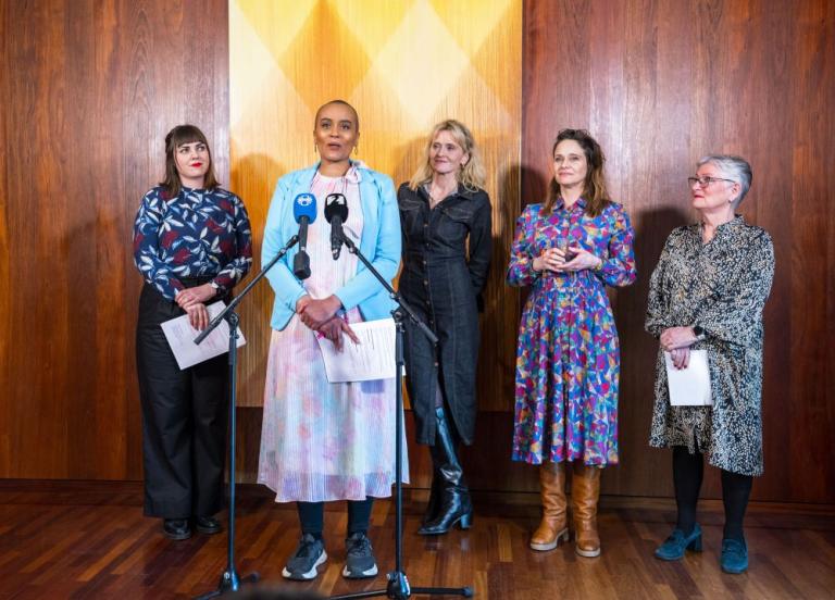 Sanna Magdalena Mörtudóttir speaks with four women standing behind her