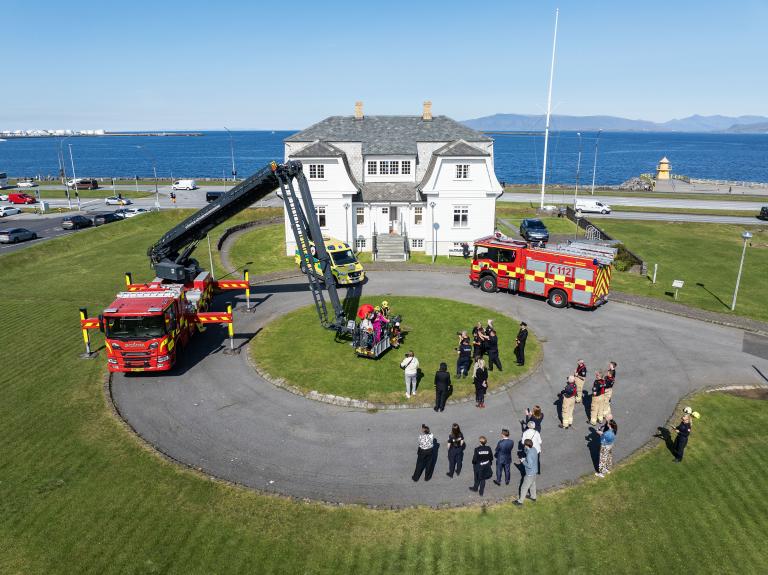 Fire trucks and ambulance lined up at Höfði in pleasant weather when fire safety bear Bjørnis was welcomed. Aerial photo.