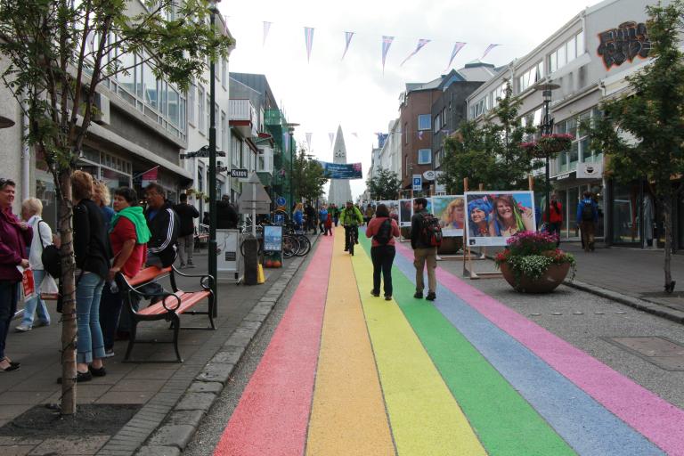 Tourists and others on Skólavörðustígur. Hallgrímskirkja church in the background, rainbow street in the foreground.
