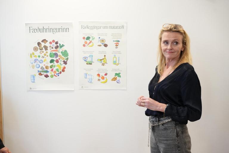 Heiða Björg borgarstjóri við plakat með ráðleggingum um mataræði.