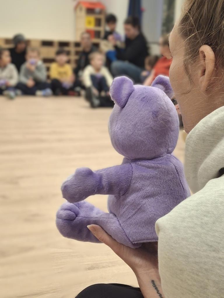 Mynd af stórum Blæ bangsa sitjandi í hring með börnunum.