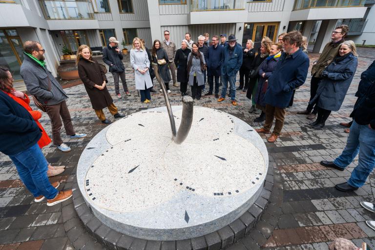 Frá vígslu útilistaverksins Rif í Vesturvin. Fólk standandi í hálfhring utan um verkið.