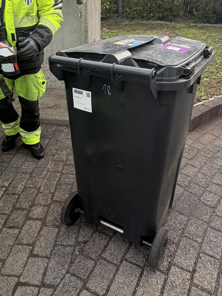 Hvítur límmiði sem búið er að koma fyrir á sorptunnu