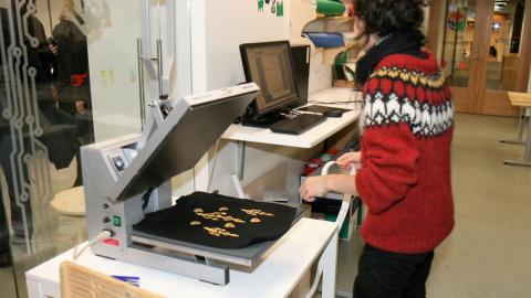 Kona þrykkir grafík á taupoka.