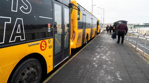 Strætisvagnar á biðstöð og fólk á leið í strætó.