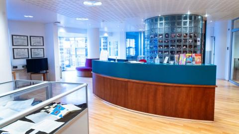 Mynd tekin innan í Borgarskjalasafni. Sýnir bogadregið borð, í forgrunni glærir kassar með sýningarskjölum.