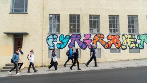 Fólk gengur framhjá vegglistaverki við Ægisgötu 7.