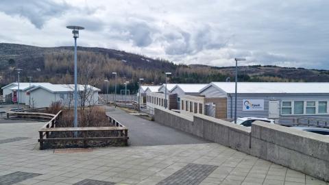 Hvít, lágreist hús sem standa í röðum. Stétt fremst á mynd og ljósastaurar.