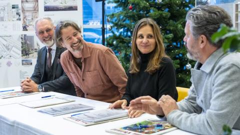 Fólk að skrifa undir samning við borð. Jólatré í baksýn.