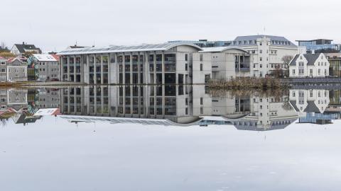 Ráðhús Reykjavíkur speglast í sléttri Tjörninni