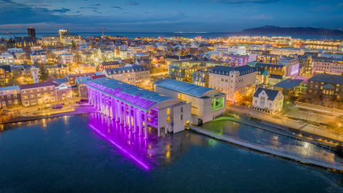 Reykjavík City Hall in winter, aerial view, illuminated with purple lights. The Kvosin area is also visible from above.