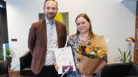 Einar Þorsteinsson and Marta Wieczorek, Reykjavík Resident of the Year 2024, pose in the mayor's office. Marta holds a bouquet and her certificate of recognition.