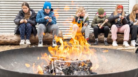 Börn sitja við varðeld.
