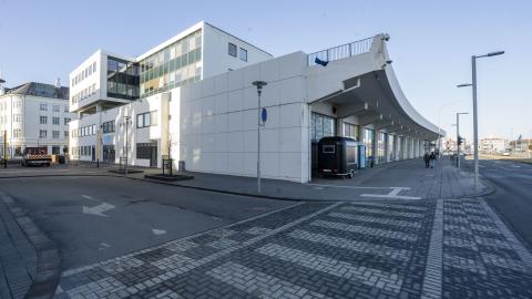 Tryggvagata 19 (Kolaportið). Photographed at an angle from the Hafnartorg area. Blue sky, with the street in the foreground.