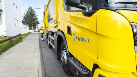 A yellow waste collection vehicle on the street.