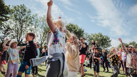 Children dancing enthusiastically in good weather at a summer festival in the Family Park.