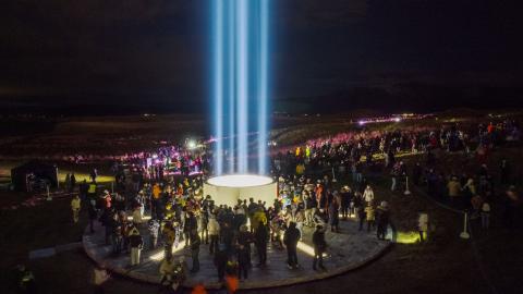 Lighting of the Imagine Peace Tower in Viðey. A crowd gathers at the tower after dark.