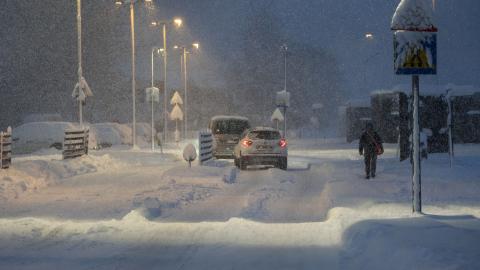 Car on a street with heavy snow and one person walking