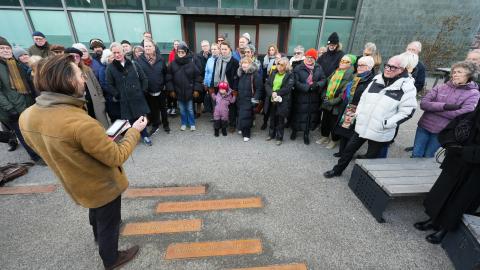 Frá afhjúpun ljóðlistaverks Sigurðar Pálssonar við Tollhúsið. Margmenni stendur í hálfhring og hlustar á Ragnar Helga Ólafsson rithöfund tala.