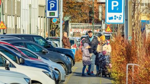 bílar við götu og fólk á gangstétt