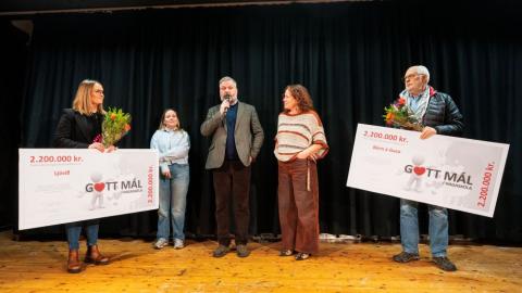 Fimm einstaklingar á sviði með tvær stórar ávísanir