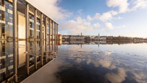 Hluti af Ráðhúsi Reykjavíkur speglast í Tjörninni í fallegu veðri
