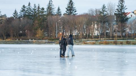 Þrír unglingar ganga yfir frosna Tjörnina í Reykjavík