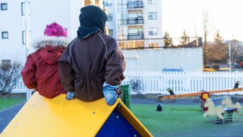 Children sitting on a small playhouse in a preschool yard.