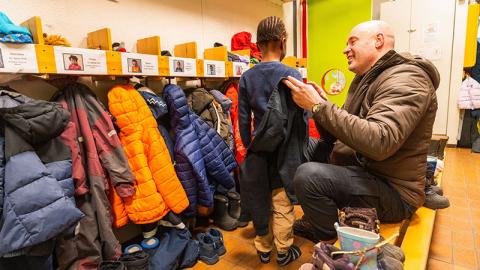 Mynd af föður og barni í fataklefa leikskóla.