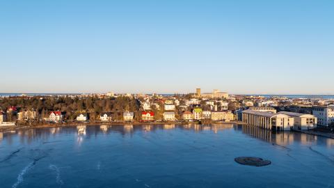 Tjörnin, Tjarnargatan, séð frá Þingholtum, loftmynd. Blá Tjörn í forgrunni, blár himinn í bakgrunni. Logn, heiður himinn.